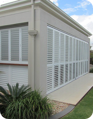 White plantation shutters enclosing a covered residential patio
