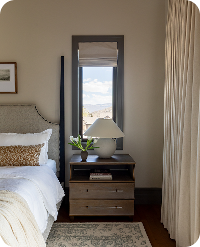 Roman shade and floor-length drapery beside a bedroom window